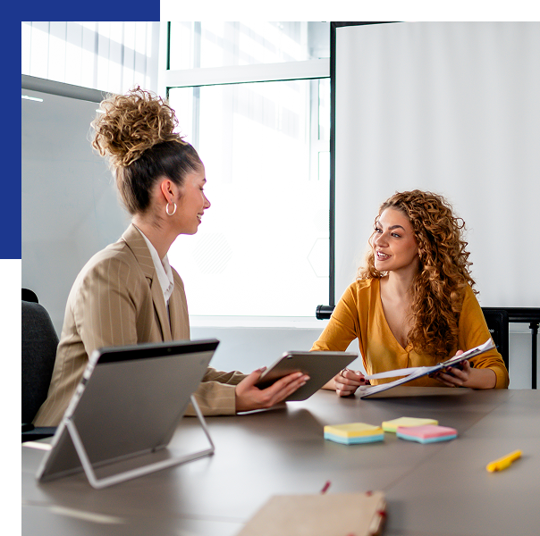 Two women discussing documents in office meeting